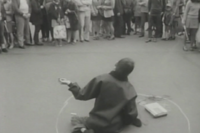 black and white film still of a human figure with cerebral palsy being isolated by the crowd