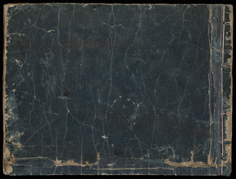 A photograph of the back cover of the Shudō tsuya monogatari manuscript, which is a black, almost dark blue color with worn edges and crackles in the paper.