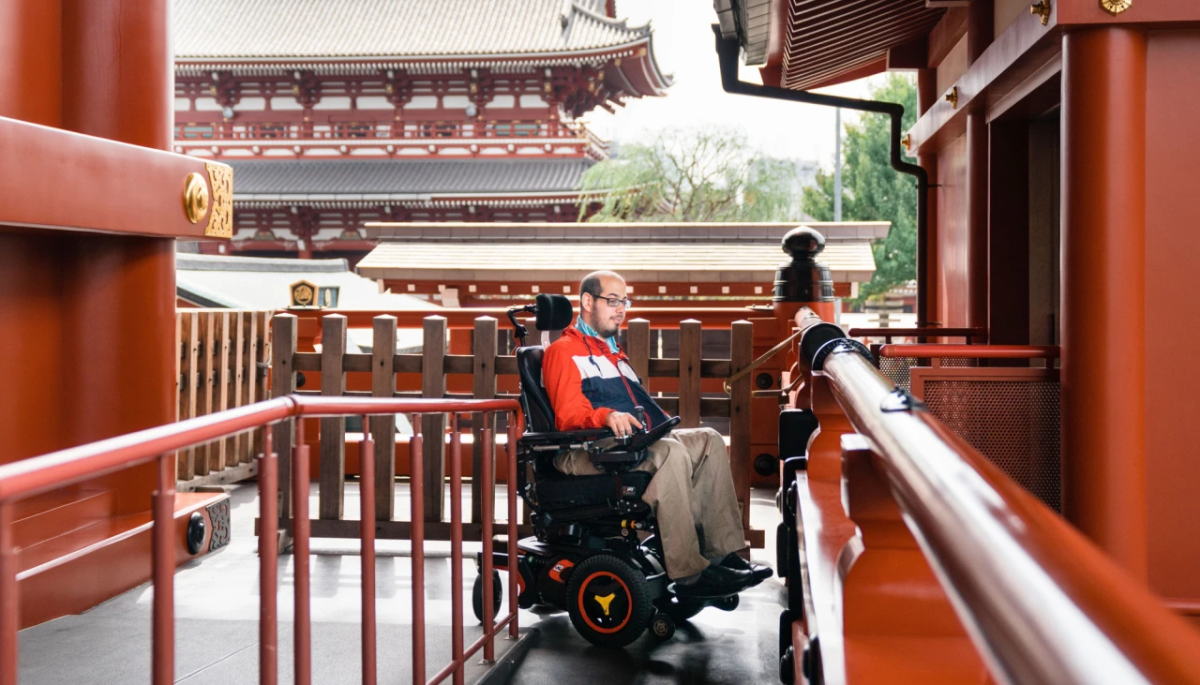 Photograph of the late Mark Bookman in a motorized wheelchair visiting a Japanese temple.