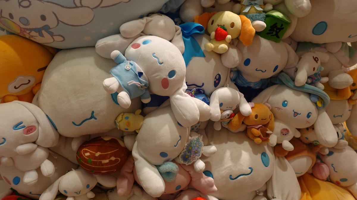 A pile of stuffed toys of various sizes, mostly of the Sanrio character Cinnamoroll, who is white with a large head and ears, with facial features stitched in baby blue and pink