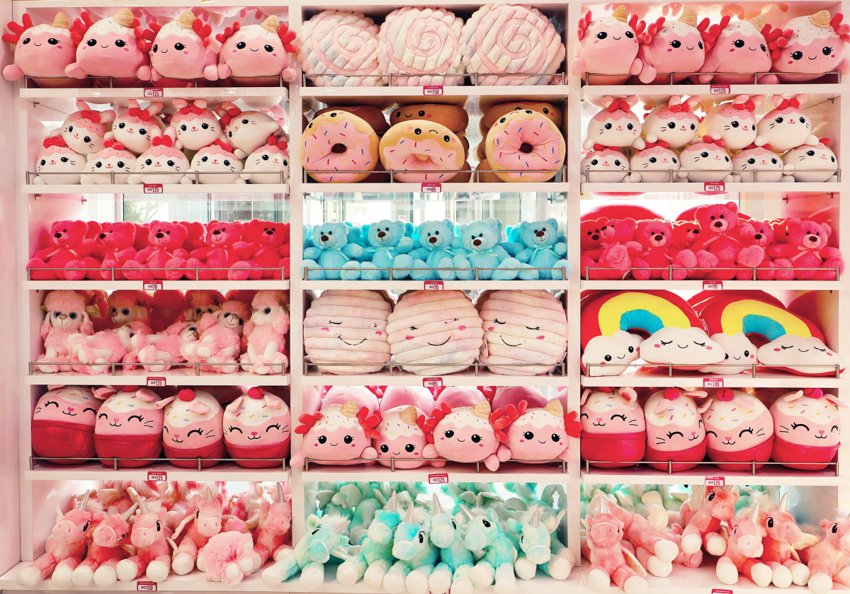 Four shelves in three columns of neatly arranged stuffed toys, organized by type and color, mostly in shades of pink