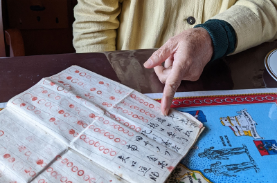 A photograph of a closeup view of Urakami Sachiko pointing at an old, historical piece of paper. She is at the Hidden Christian Museum, Naru Island.