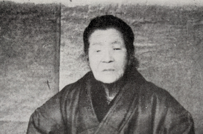 Partial view of a black and white photograph of an elderly Japanese woman dressed in kimono. Her name was Urakawa Mori and she was a a Sempuku Kirishitan Hidden Christian and survivor of the Urakami Fourth Persecution.
