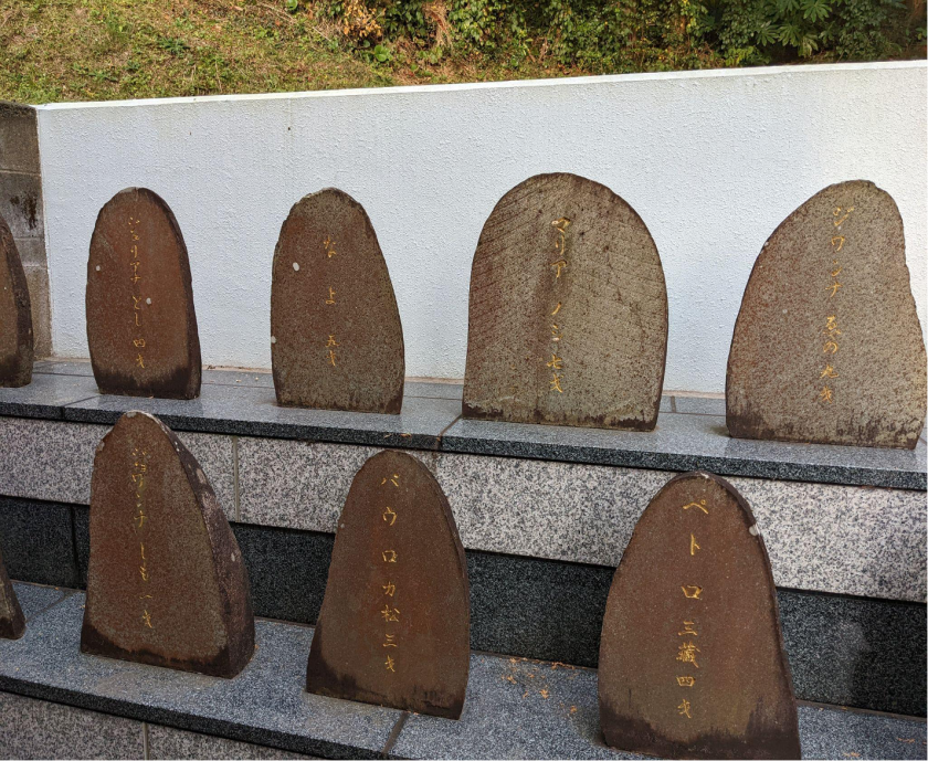 Photograph of two rows of stone plaques at a memorial site. The names are colored in gold.