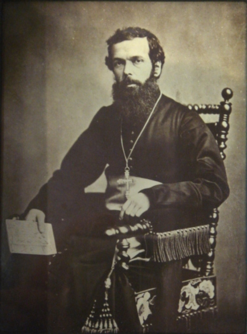 A photograph of Bernard Thaddée Petitjean. A middle-aged Caucasian Catholic priest with long black beard with a cross dangling from his neck, seated in chair.