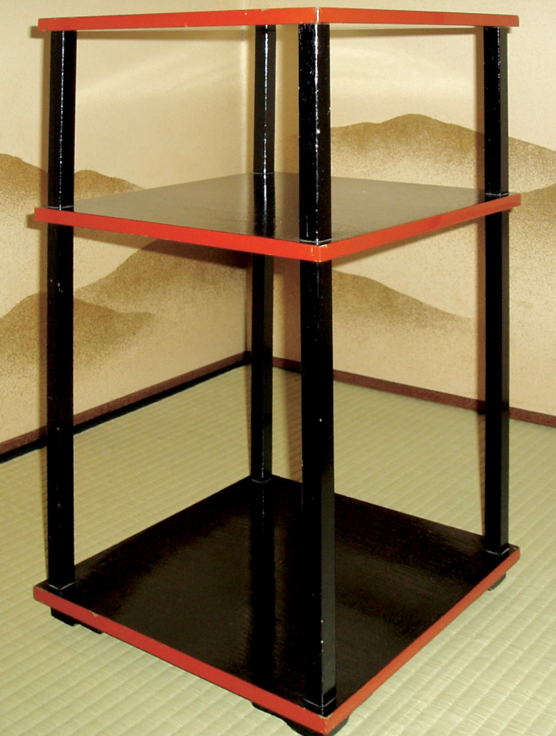 A black lacquer three level stand with red lacquered edge.