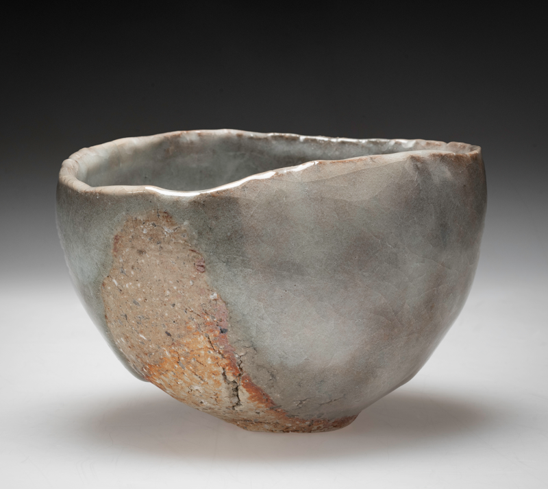 A cloudy gray teabowl with an irregular lip and textured orange spots on the surface.