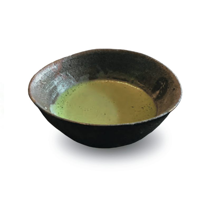 A brown, wide-rimmed tea bowl with bright green tea inside.